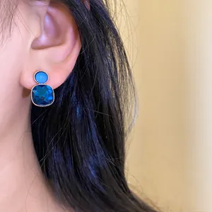 Detailed view of blue geometric crystal stud earrings worn by a model in soft lighting