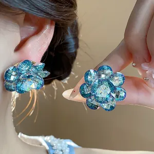 Close-up of vibrant blue glass flower stud earrings with shimmering multifaceted petals
