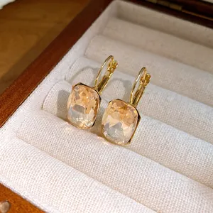 Close-up of elegant champagne square gemstone pendant earrings in a wooden jewelry box