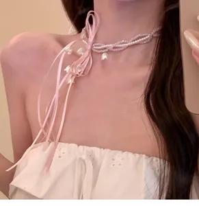 Detailed view of sweet pink beaded necklace with ribbon bow and lily of the valley flowers