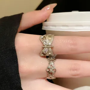 Detail view of vintage-style zircon butterfly and bow patterned open rings on finger