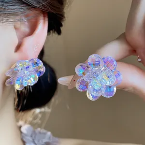 Close-up detail of shimmering iridescent glass flower stud earrings with multi-faceted petals.