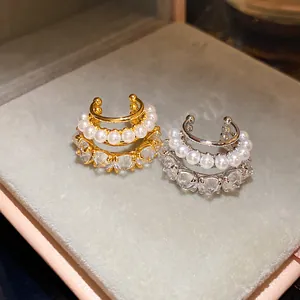 Detailed macro shot of gold and silver heart-shaped zircon ear cuffs adorned with elegant pearls