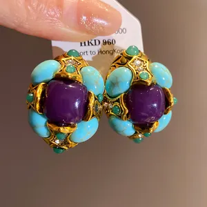 Detailed macro view of vintage palatial style earrings with purple resin and turquoise stones