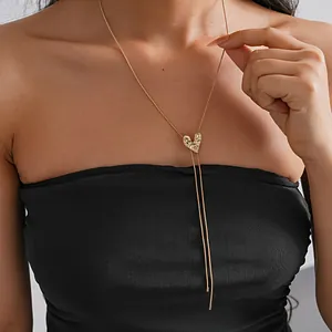 Elegant gold heart pendant necklace with long tassels displayed on a female model