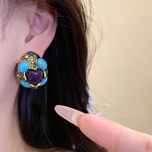 Close-up of vintage palace style earring with turquoise resin and purple heart stone.