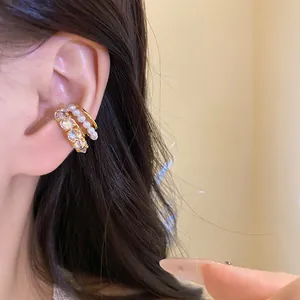 Close-up detail showing elegant zircon and pearl non-piercing gold ear cuffs on ear.