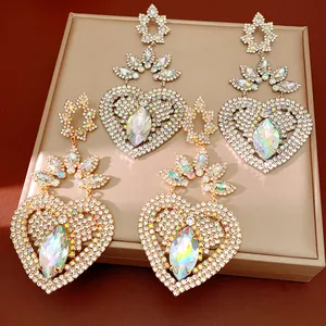 Close-up of sparkling heart-shaped rhinestone dangle earrings in gold and silver tones.