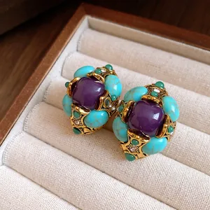 Close-up of vintage palace style earrings with purple resin and turquoise stones.