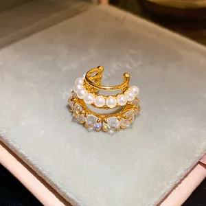 Macro shot showing the pearl and zircon details on a triple-layer gold ear cuff.