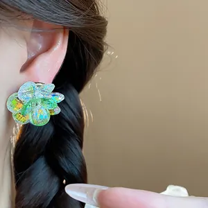 Detailed close-up of vibrant iridescent glass flower stud earrings worn on an ear