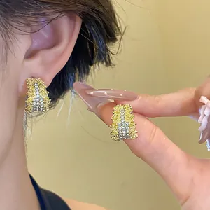 Detailed close-up view of gold C-shaped earrings with shimmering pave-set crystals.
