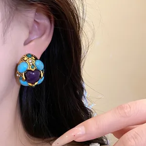 Close-up of vintage palace-style earrings with purple heart and turquoise resin