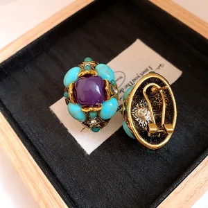 Close-up of vintage court-style oval earrings with purple resin and turquoise stones