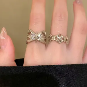 Macro view showing intricate butterfly and vintage zircon ring details on fingers