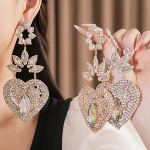 Close-up detail of oversized heart earrings with iridescent crystals and rhinestones.