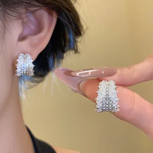 Detailed view of elegant silver needle C-shaped earrings encrusted with sparkly rhinestones