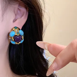 Close-up view of vintage court-style resin earring with turquoise and purple heart detail
