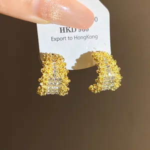 Detailed view of exquisite diamond-encrusted C-shaped gold stud earrings with silver needles