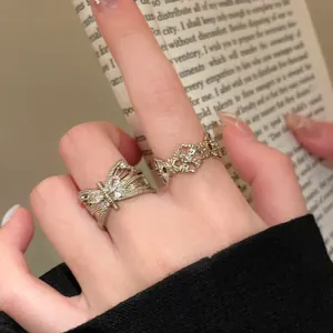Close-up detail of a vintage style butterfly zircon open ring and filigree band on finger.
