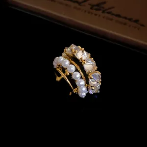 Close-up of elegant gold-toned ear cuff featuring white pearls and sparkling zircons