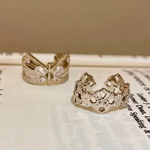 Close-up of vintage style zircon butterfly and floral pattern open rings on a book page.