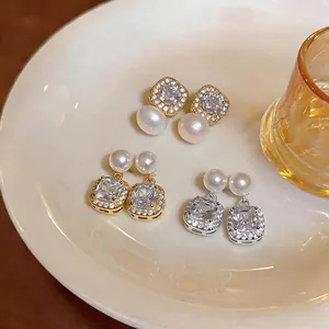 Detailed close-up of vintage pearl earrings with square cubic zirconia on a plate