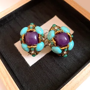 Close-up of vintage style gold-tone earrings with purple resin and turquoise stones