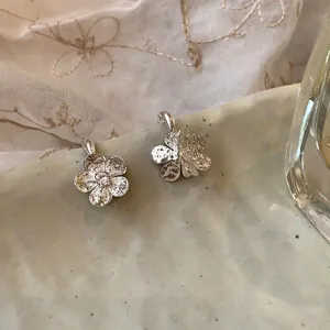 Vue macro détaillée de boucles d'oreilles en argent aux pétales froissés fleuris.