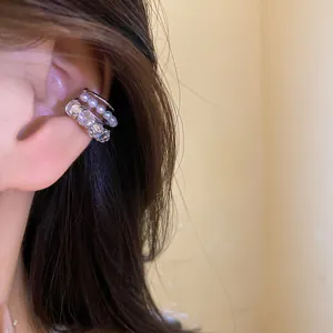 Macro view of elegant triple layered zircon and pearl ear cuff on ear cartilage