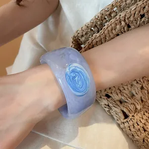 Macro view of marbled resin bangle featuring a blue swirl pattern on a wrist