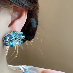 Close-up of iridescent blue crystal flower stud earring worn on ear for women