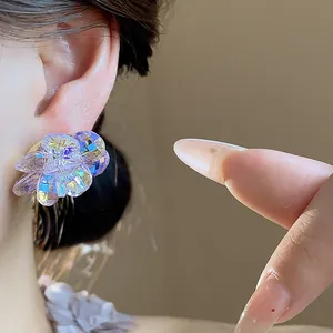 Close-up macro shot of a sparkling crystal flower stud earring worn on a female ear