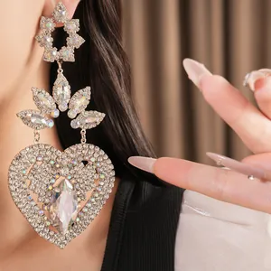 Close-up of sparkling heart-shaped dangle earrings with rhinestone flower details