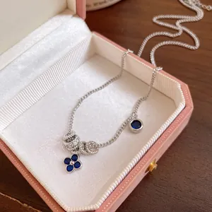 Detail showing blue flower pendant and zircon charms on a silver necklace in a gift box.