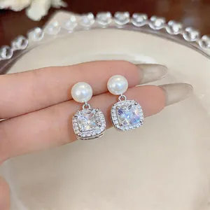 Close-up of elegant pearl drop earrings with square zircon halo in silver finish