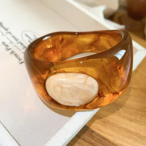 Close-up of vintage amber resin bangle featuring marbled texture and cream oval inlay