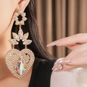 Detailed macro view of luxurious oversized heart-shaped gold earrings with sparkling rhinestones.