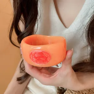 Detailed macro view of wide resin bangle with orange marble texture and red wax seal motif