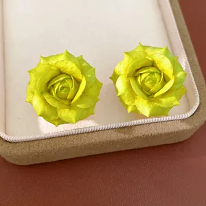 Macro view of exquisite yellow rose stud earrings presented in a beige jewelry box