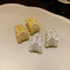 Macro detail of luxury C-shaped silver stud earrings with sparkling pavé diamonds