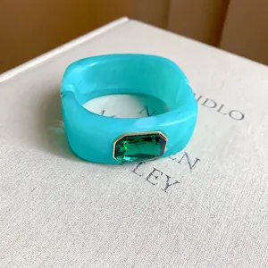 Stylish turquoise square resin bangle featuring a large emerald-green gemstone centerpiece.