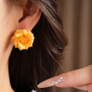 Detailed view of an elegant yellow rose flower stud earring worn on a model's ear