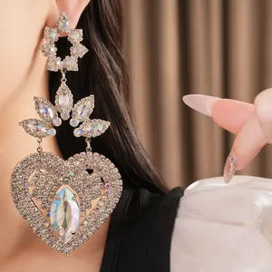 Close-up view of large silver heart-shaped drop earrings adorned with sparkling iridescent crystals