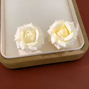 Close-up of elegant cream white rose flower stud earrings in a jewelry box