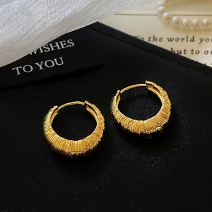 Elegant gold textured hoop earrings with a pleated surface on a black gift box