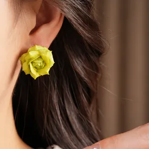 Close-up shot of 18K gold plated silver flower stud earrings on an Asian model ear.