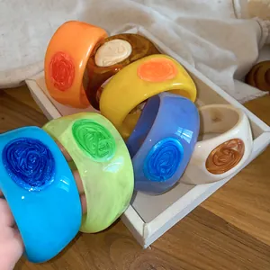 Detailed view of colorful resin bangles with swirled textures and drip oil centers.