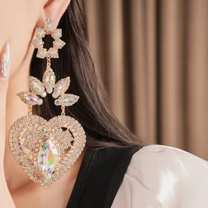 Detailed macro view of luxury ornate rhinestone heart dangle earrings on model's ear