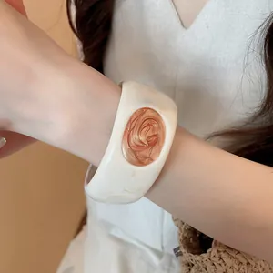 Close-up detail of a creamy white resin bangle with a brown swirl oil-dripping inset